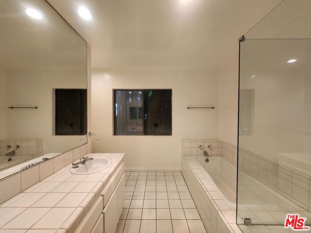 a spacious bathroom with a tub shower and a sink