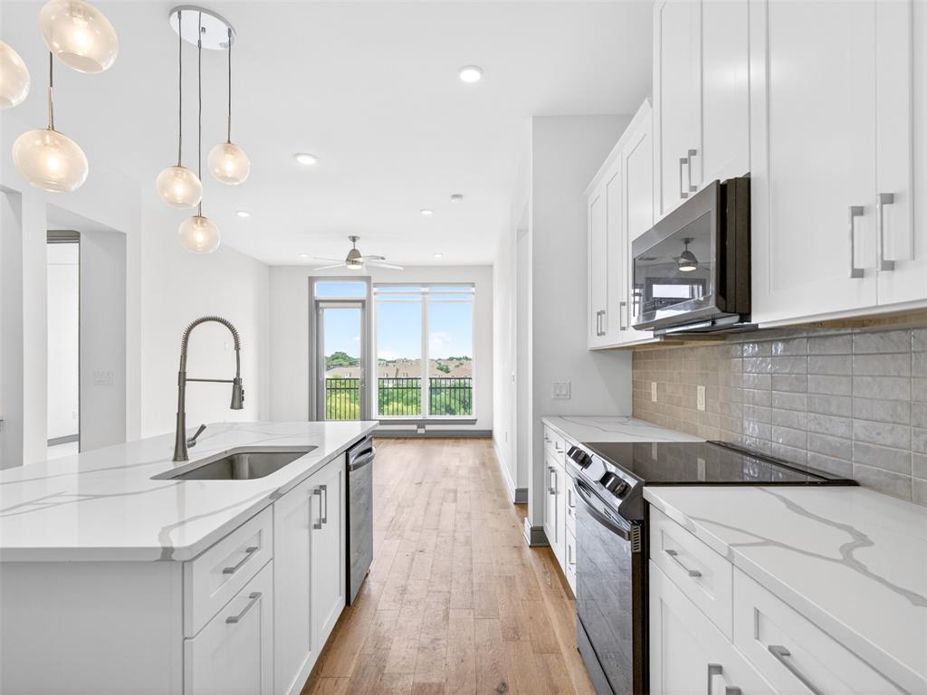 Modern kitchen featuring white cabinetry, light-toned countertops with distinctive veining, and a stainless steel sink with a gooseneck faucet