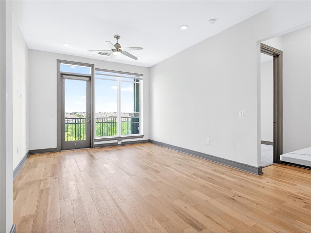 2700 Old Denton Road, Unit 4440 Carrollton, TX 75007 - Photo 15 of 32 Spacious room featuring wood-finish flooring, a full-lite exterior door, large windows, a ceiling fan, and recessed lighting