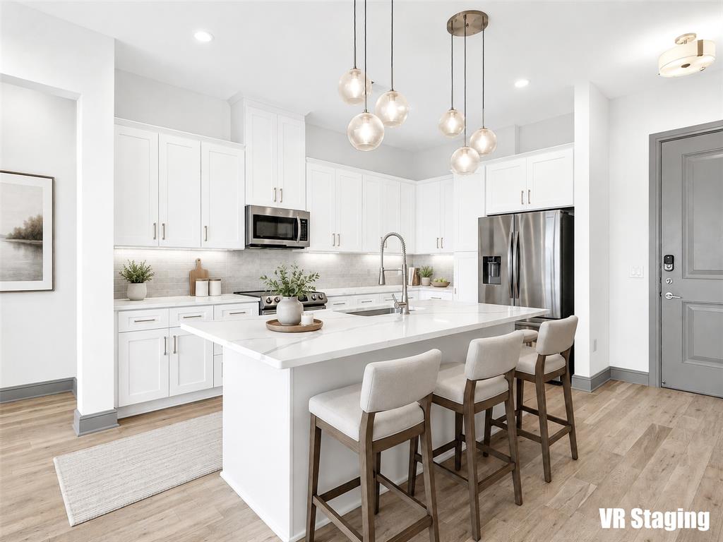2700 Old Denton Road, Unit 4440 Carrollton, TX 75007 - Photo 2 of 32 Modern kitchen featuring white shaker cabinetry, stainless steel appliances, a center island with countertop seating, and wood-finish flooring