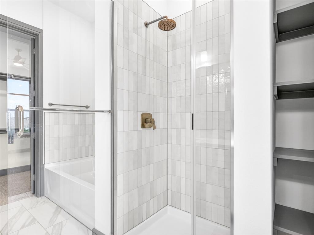2700 Old Denton Road, Unit 4440 Carrollton, TX 75007 - Photo 31 of 32 Shower enclosure featuring vertical tile accents, a rain shower head, and a bronze-finish control