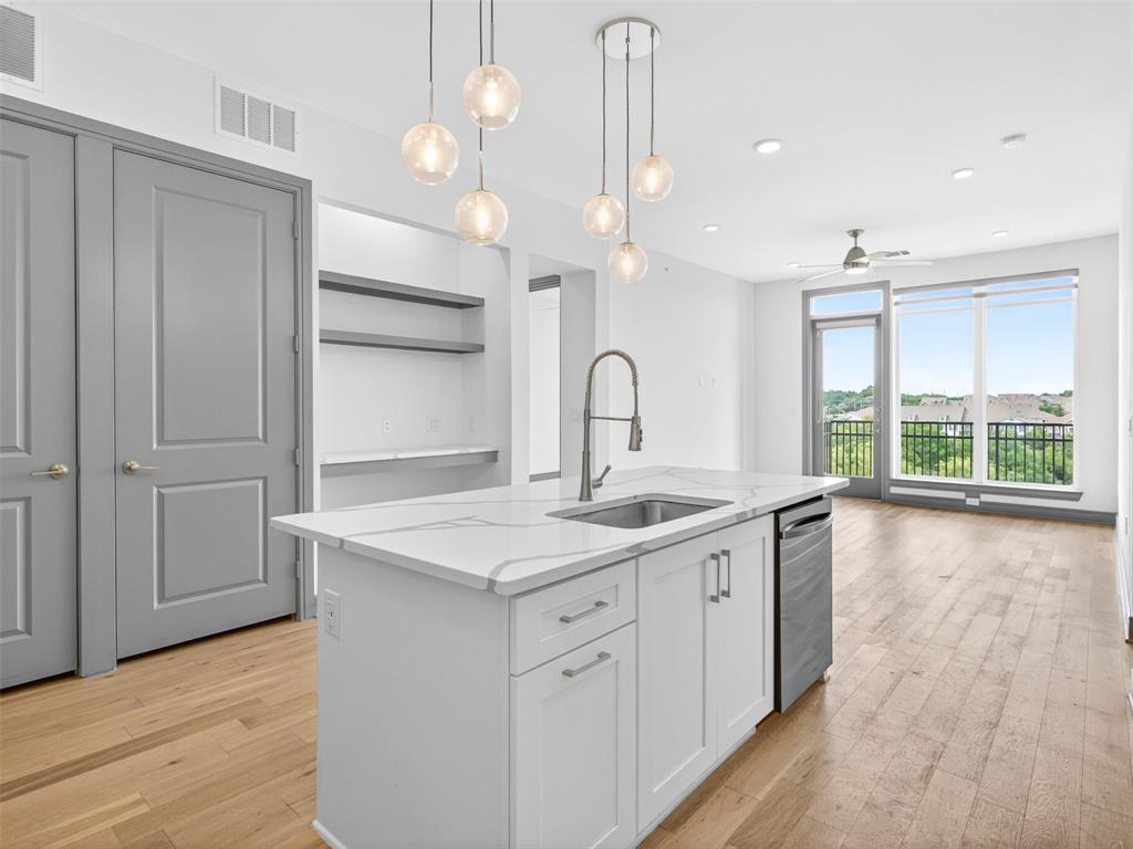 2700 Old Denton Road, Unit 4440 Carrollton, TX 75007 - Photo 4 of 32 Central kitchen island with a quartz countertop and integrated sink, complemented by pendant lighting