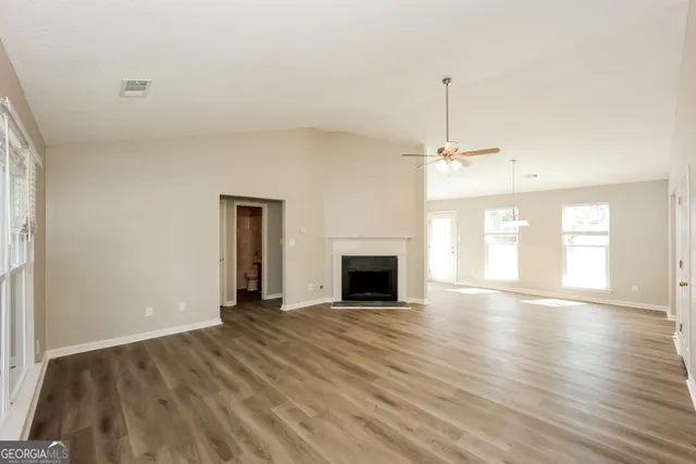 a view of empty room with wooden floor fireplace and window
