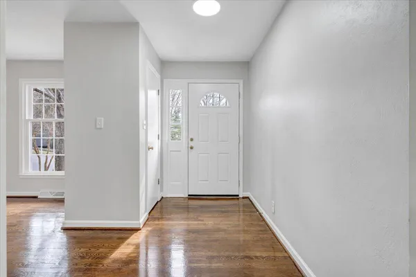 an empty room with wooden floor & windows