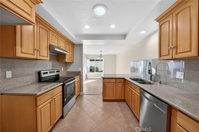 a kitchen with stainless steel appliances granite countertop a sink stove refrigerator granite counter tops and a wooden cabinets