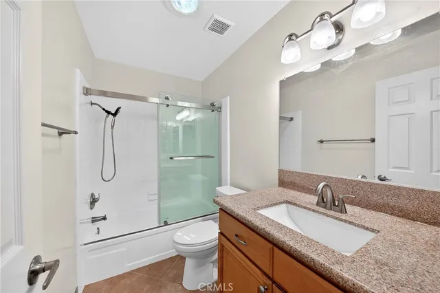 a bathroom with a granite countertop sink a toilet and shower