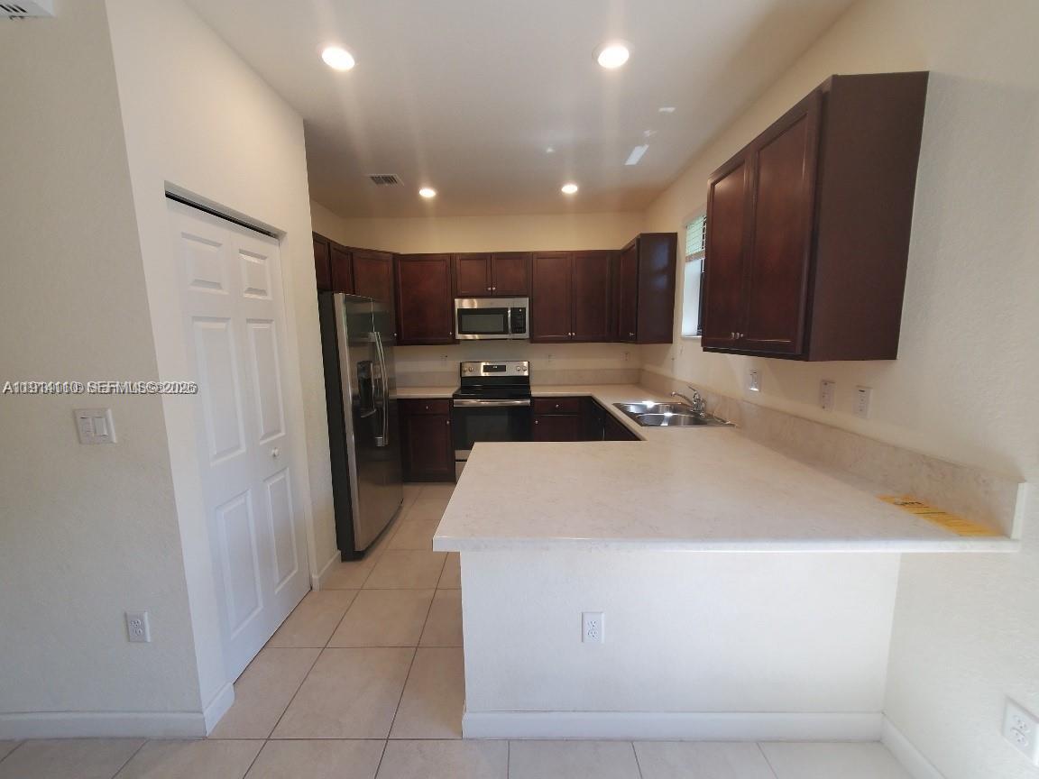 110 Southeast 33rd Terrace Homestead, FL 33033 - Photo 2 of 11 a kitchen with kitchen island granite countertop wooden cabinets and a refrigerator