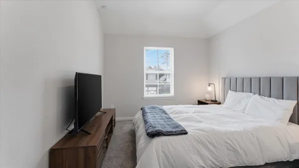 a bedroom with a bed tv and a window