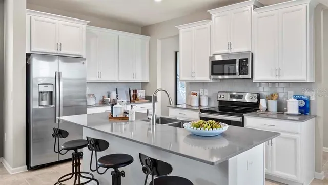 a kitchen with stainless steel appliances granite countertop a refrigerator a stove a sink a stove and white cabinets