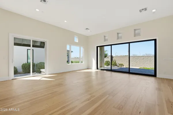 a view of an empty room with a window and wooden floor