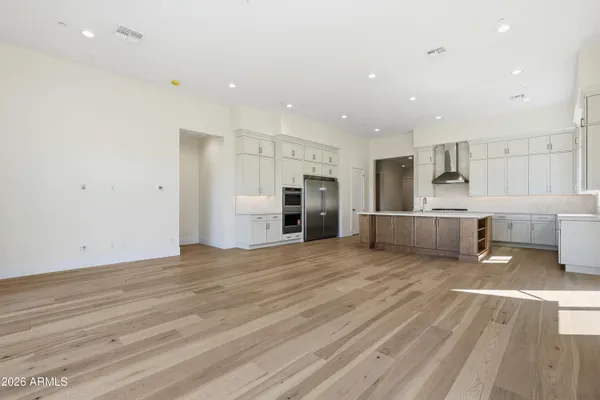 a large white kitchen with a lot of counter space and stainless steel appliances