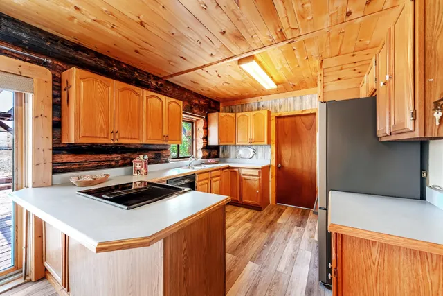 a kitchen with stainless steel appliances a stove a refrigerator a sink dishwasher and wooden cabinets with wooden floor