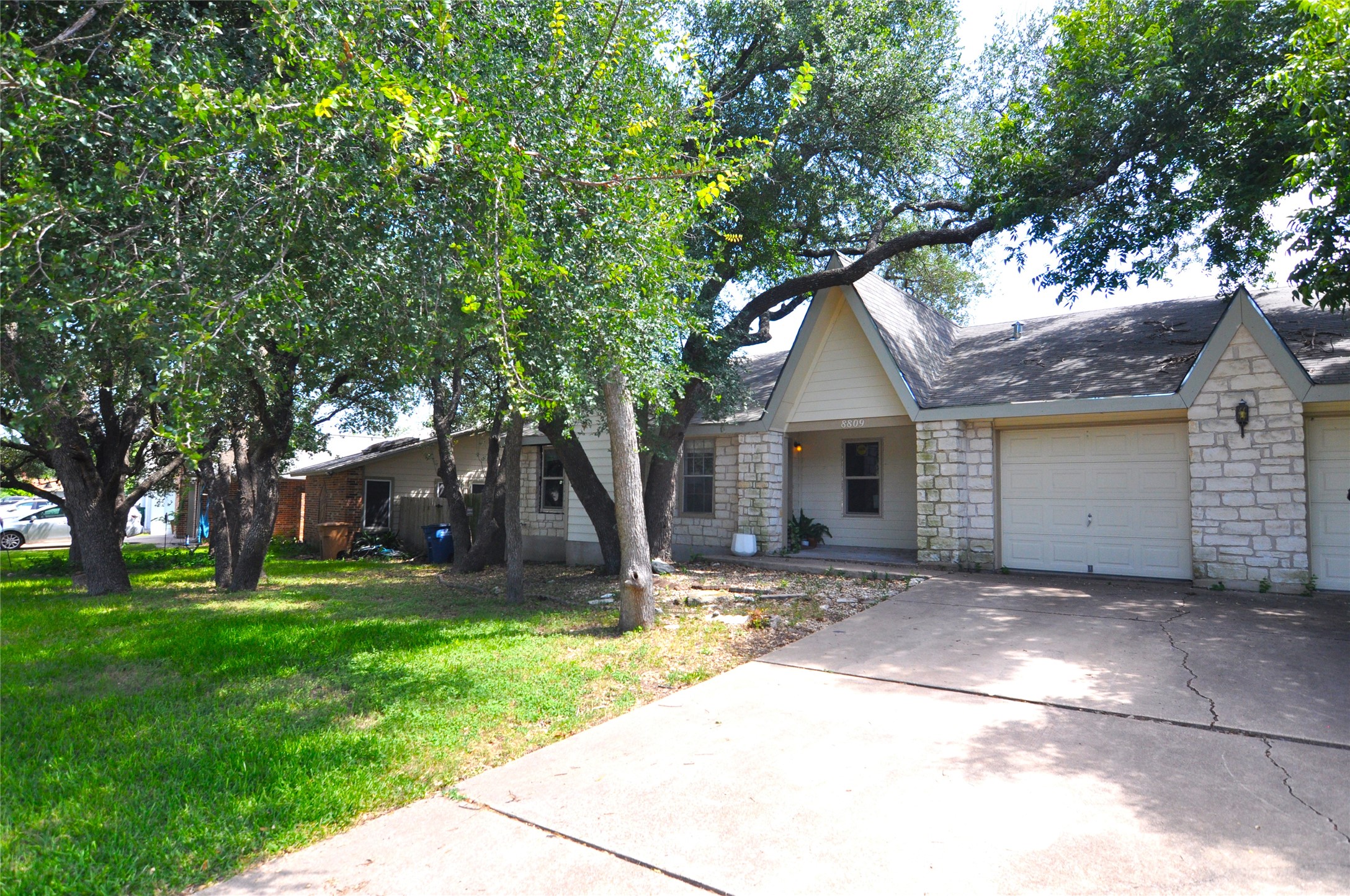 8809 Piney Point Drive, Unit B Austin, TX 78729 - Photo 1 of 10 Mature trees frame this charming residence with a stone facade and attached garage.