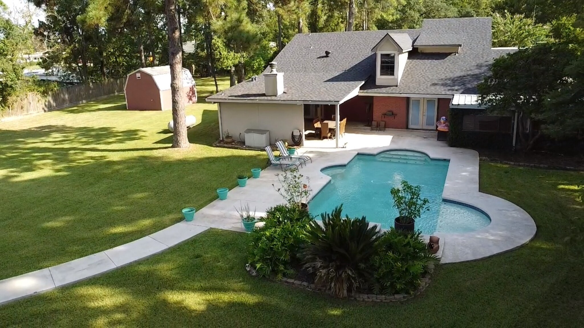 1300 Smith Road Huffman, TX 77336 - Photo 48 of 50 Backyard oasis features sparkling pool, lush greenery, and a cozy covered patio for ultimate relaxation and entertaining.