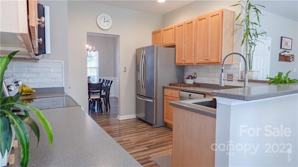 3303 Burnage Hall Road Harrisburg, NC 28075 - Photo 10 of 37 a kitchen with stainless steel appliances granite countertop a sink a stove a refrigerator a dining table and chairs with wooden floor