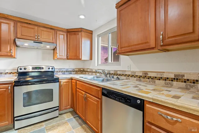 a kitchen with stainless steel appliances granite countertop a sink stove and cabinets