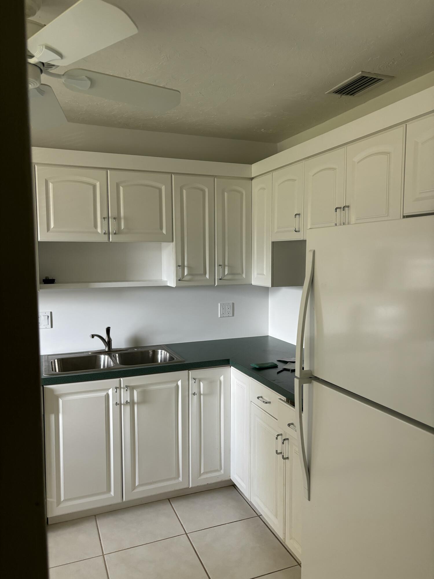 1700 Dover Road, Unit 215A Delray Beach, FL 33445 - Photo 6 of 23 a kitchen with white cabinets and refrigerator