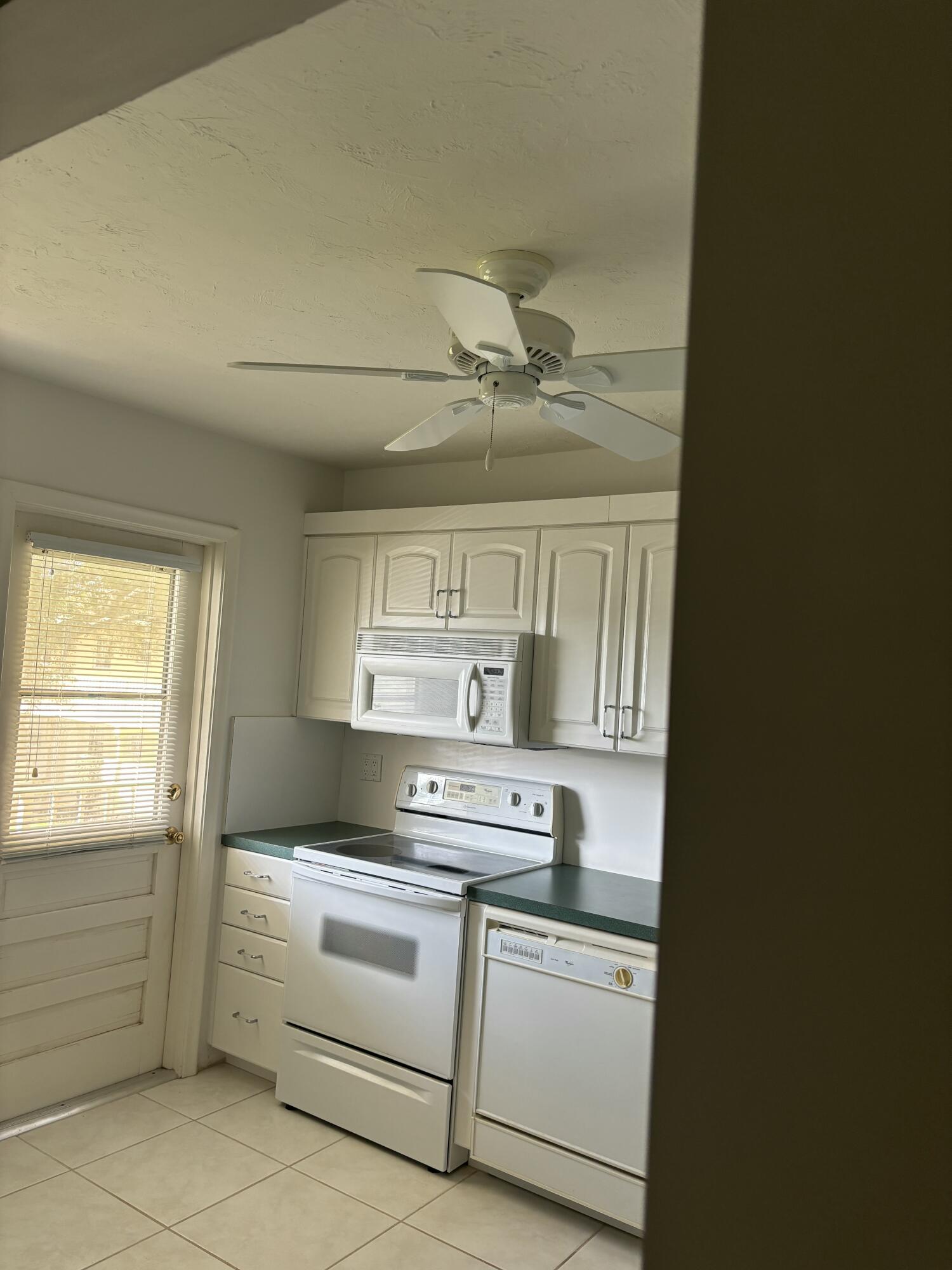 1700 Dover Road, Unit 215A Delray Beach, FL 33445 - Photo 7 of 23 a kitchen with white cabinets and white appliances