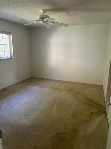 an empty room with a ceiling fan and window
