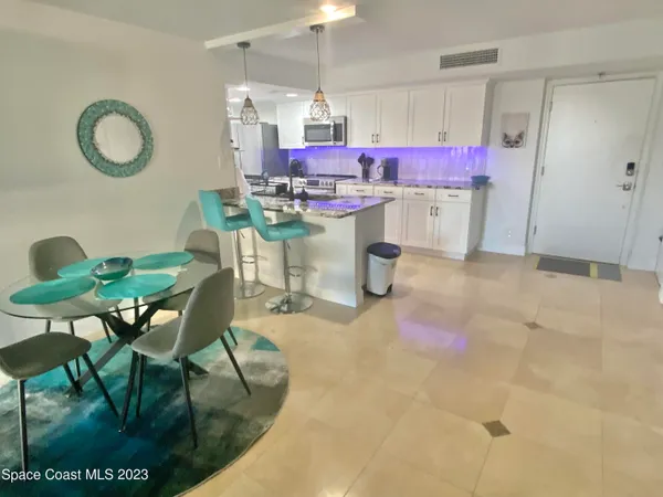 a kitchen with a sink dishwasher a dining table chairs and a refrigerator