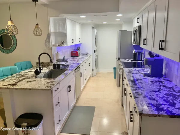 a large kitchen with stainless steel appliances granite countertop a stove a sink dishwasher and a dining table with wooden floor