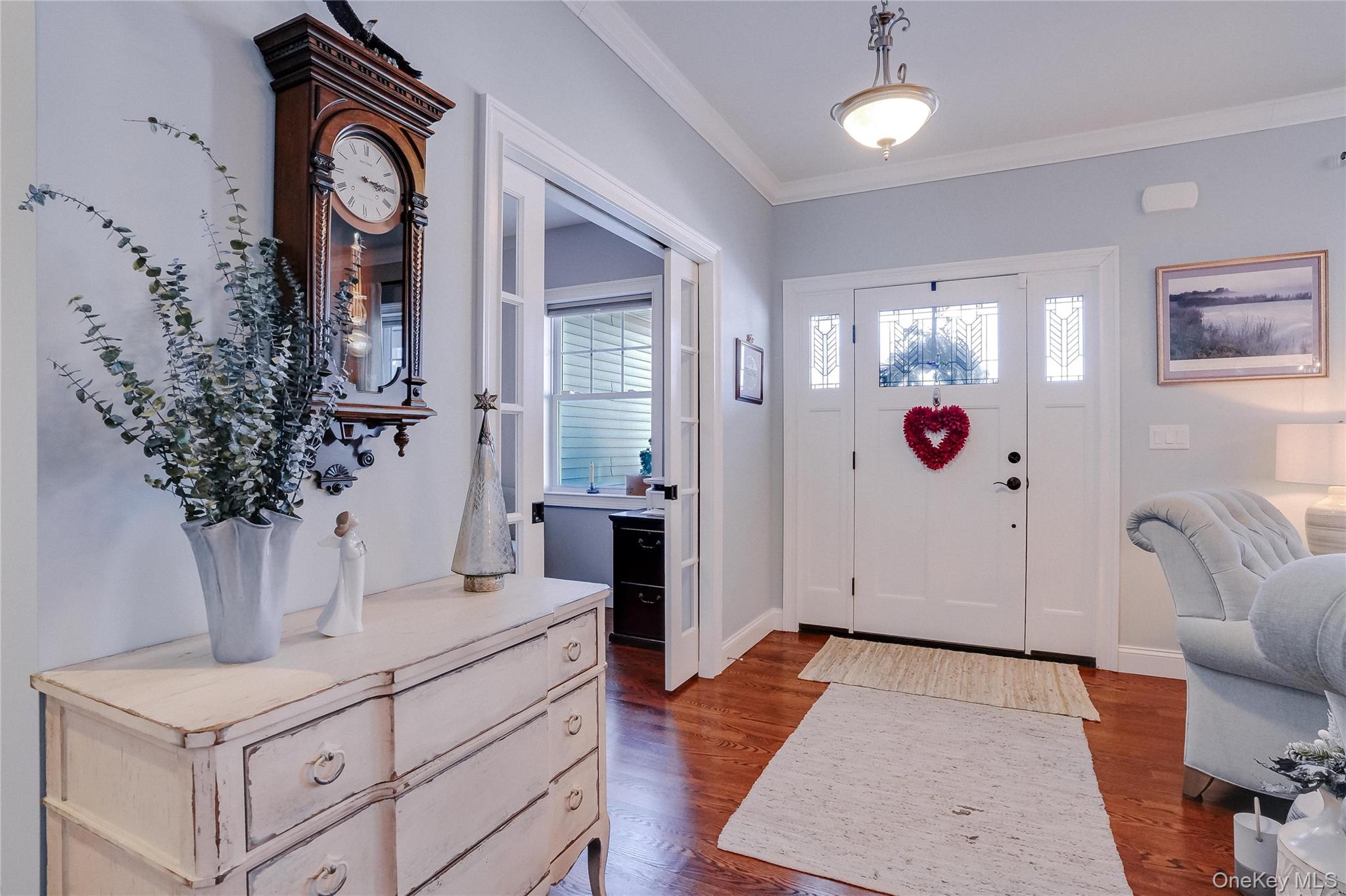 23 Swan Holw Road New Windsor, NY 12553 - Photo 5 of 34 A beautiful entrance welcomes you inside, featuring rich hardwood floors that immediately convey warmth and quality craftsmanship. The stunning stained-glass front door serves as a striking focal point, allowing soft natural light to filter through while adding timeless character and charm. This inviting foyer sets the tone for the home, offering a memorable first impression and a glimpse of the thoughtful details found throughout.