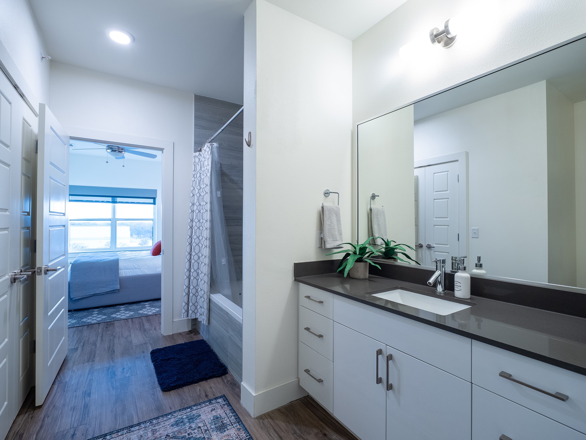 6444 Burnet Road, Unit 509 Austin, TX 78757 - Photo 17 of 32 A well-lit bathroom features a spacious vanity with an integrated sink and offers a peek into an adjoining bedroom.