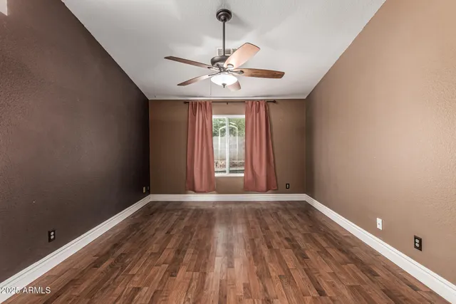 an empty room with wooden floor and fan