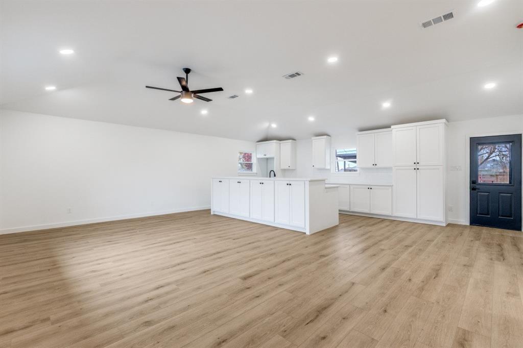 109 East 5th Street Prosper, TX 75078 - Photo 6 of 25 a view of a kitchen with a sink dishwasher refrigerator with white walls and wooden floor