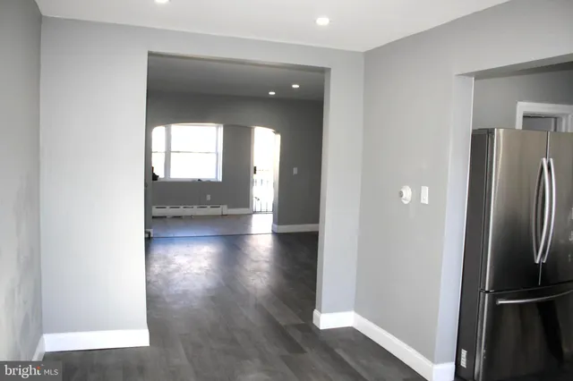a view of a hallway with wooden floor and a living room