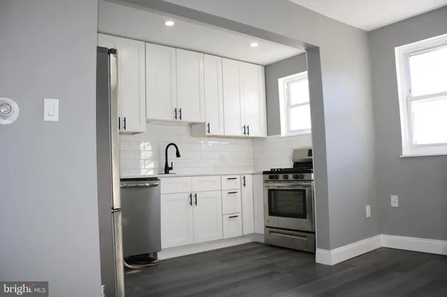 a kitchen with granite countertop white cabinets and stainless steel appliances