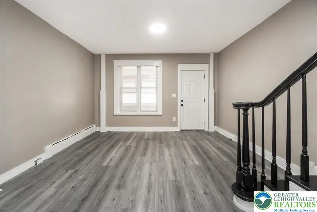 a view of an empty room with wooden floor and a window