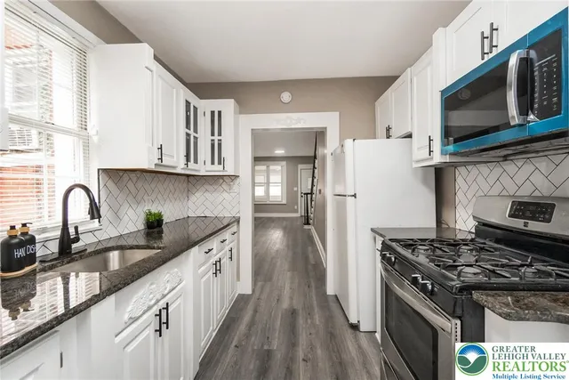 a kitchen with granite countertop a sink a stove and cabinets