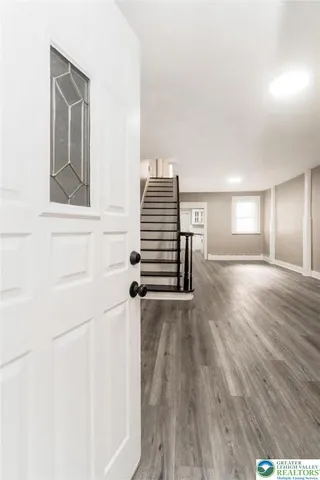 a view of an empty room with wooden floor and stairs