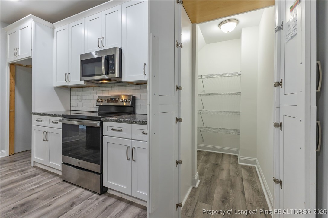502 North Stewart Street Raeford, NC 28376 - Photo 11 of 48 a kitchen with white cabinets and stainless steel appliances