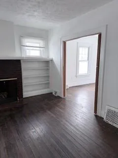 an empty room with wooden floor cabinets and windows