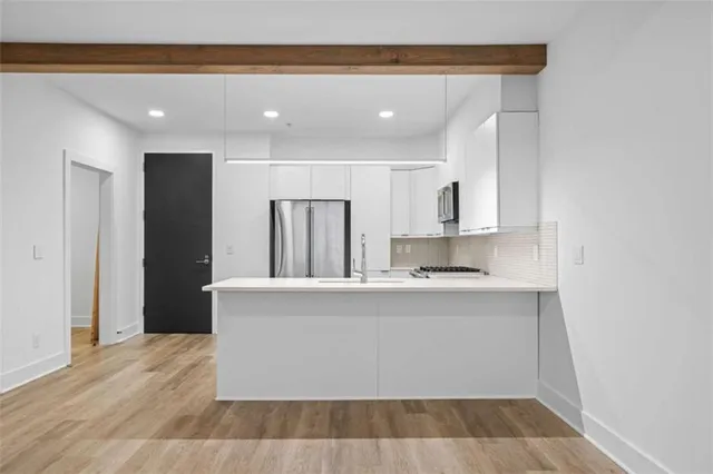 a living room with stainless steel appliances kitchen island granite countertop a refrigerator and a sink