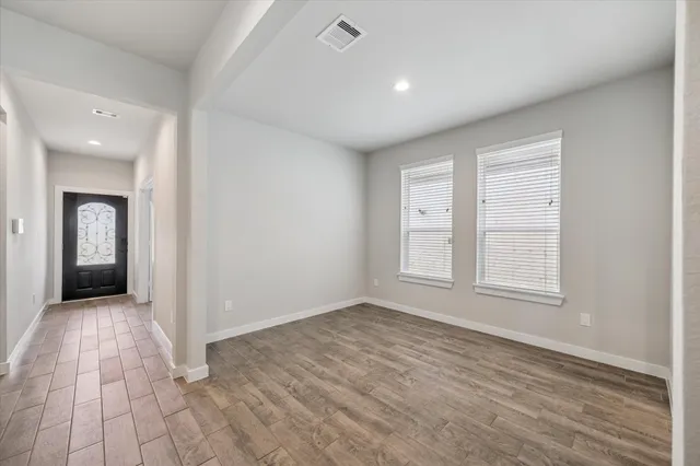 an empty room with wooden floor and windows