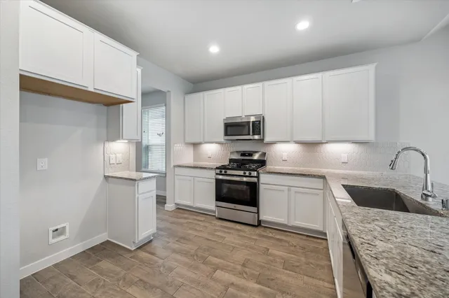 a kitchen with stainless steel appliances granite countertop a refrigerator sink and stove