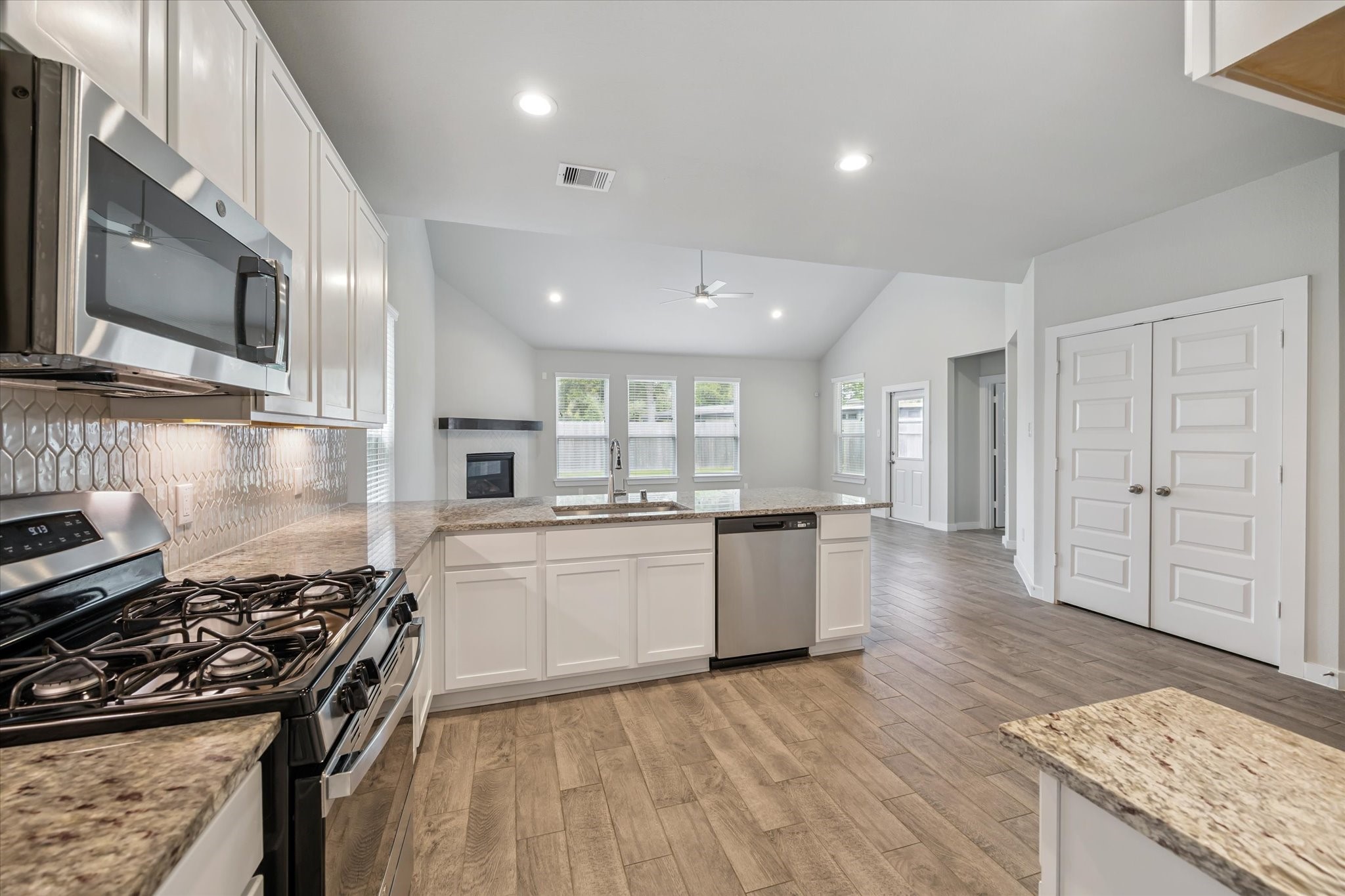 2138 Reed Cave Lane Spring, TX 77386 - Photo 7 of 23 a kitchen with granite countertop a stove top oven a sink dishwasher and white cabinets with wooden floor