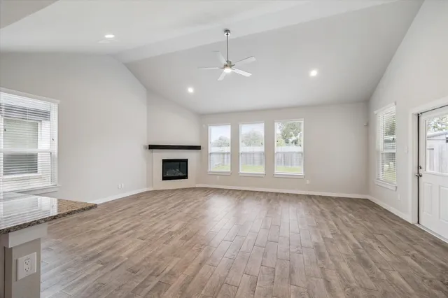 an empty room with wooden floor fireplace and windows