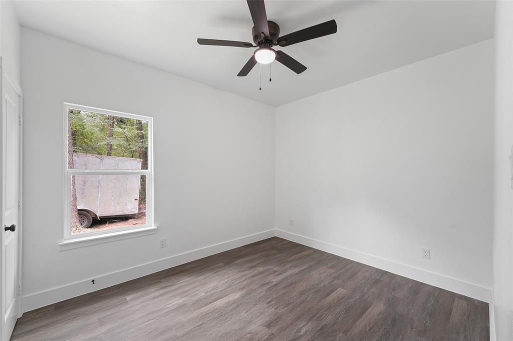 122 East Beachwood Loop Trinidad, TX 75163 - Photo 28 of 35 Bright interior space featuring a window with exterior views, wood-finish flooring, white walls, and a ceiling fan with integrated lighting