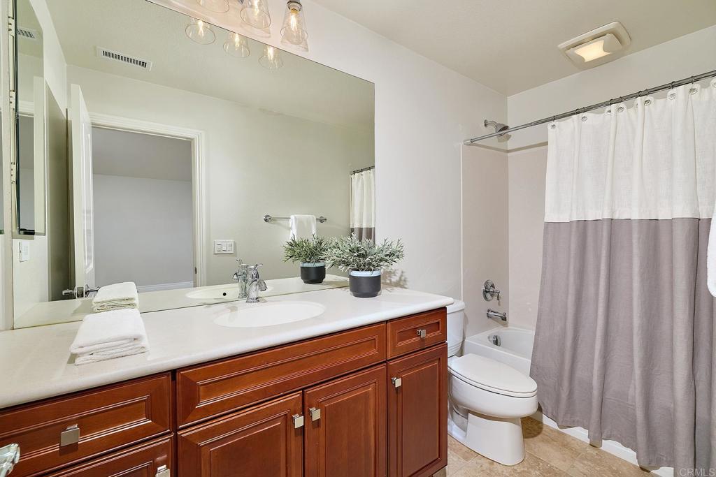 3230 Corte Aliso Carlsbad, CA 92009 - Photo 14 of 23 a bathroom with a sink a toilet a mirror and shower curtain