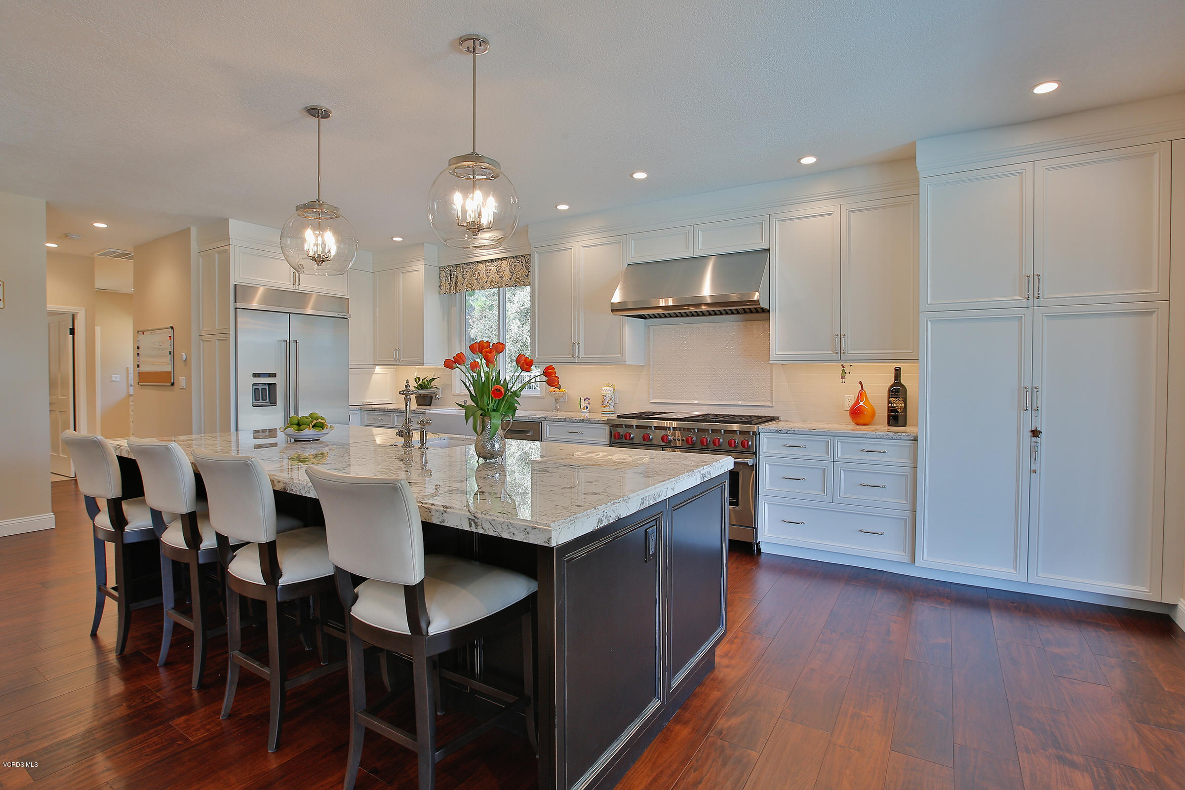 a kitchen with stainless steel appliances kitchen island granite countertop a table chairs and a refrigerator