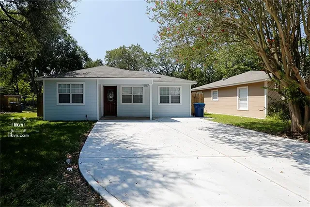 a view of a house with a yard and large tree