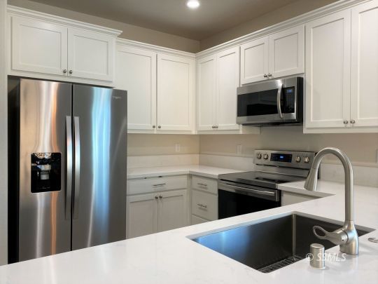1517 Mayo Street Ridgecrest, CA 93555 - Photo 6 of 32 a kitchen with stainless steel appliances granite countertop a refrigerator stove a sink and white cabinets