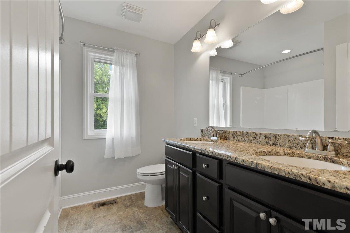 11208 Range Road Rougemont, NC 27572 - Photo 23 of 40 a bathroom with a granite countertop sink a toilet a mirror and a window
