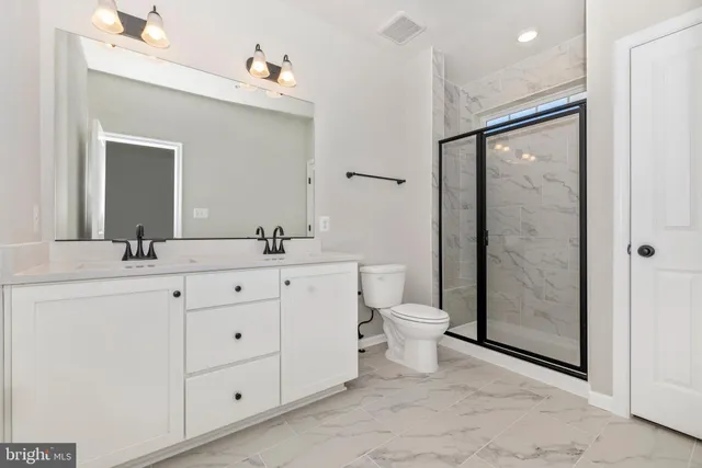 a bathroom with a double vanity sink toilet mirror and shower