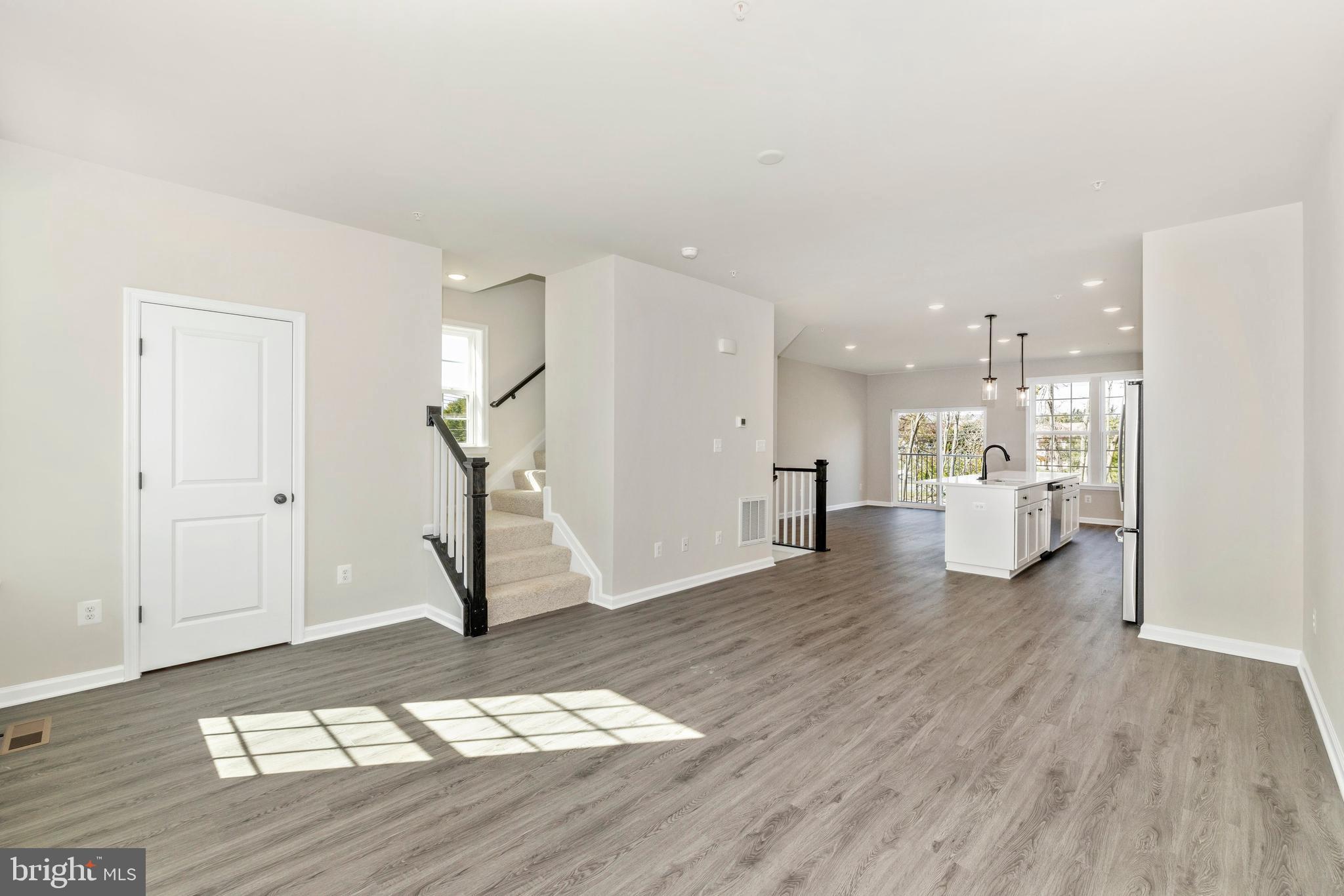 101 Spring Bank Way Frederick, MD 21701 - Photo 6 of 20 a view of an empty room and kitchen with wooden floor