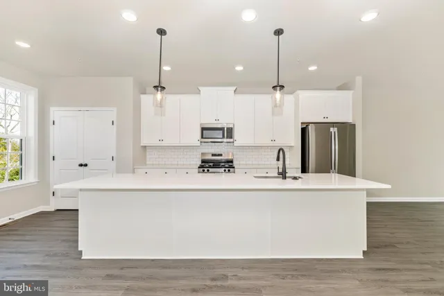 a large kitchen with kitchen island a stove a sink a center island and wooden floor